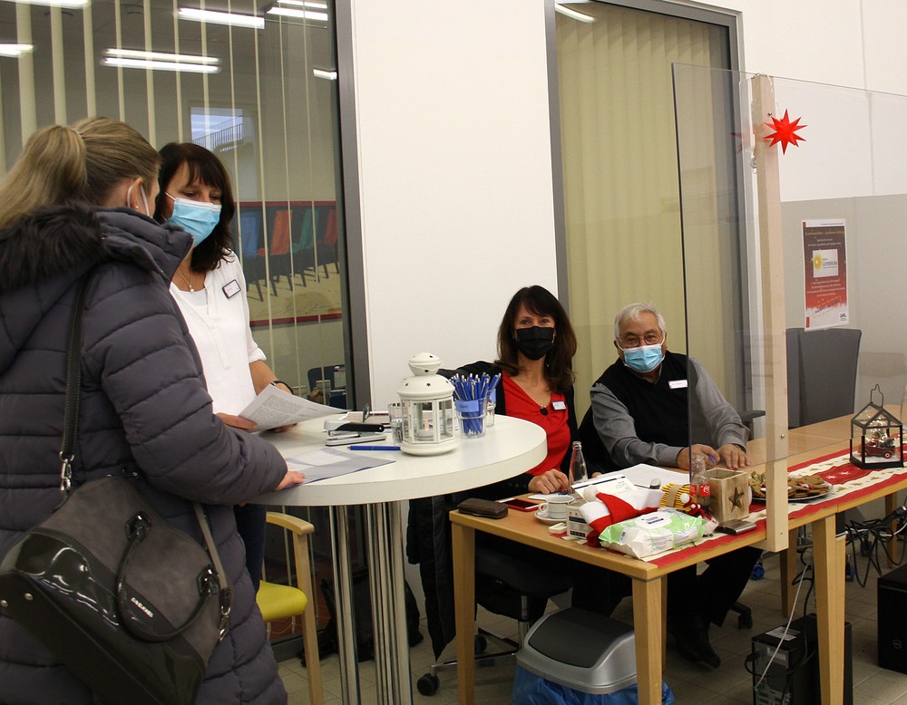 Mehrere Personen sitzen an einer Anmeldung, eine Frau füllt an einem tehtisch ein etwas aus. (Bild: LWL/SchuFi)