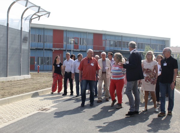 Ein Gruppe von Menschen geht innen an dem hohen Plexiglaszaun vorbei. (Bild: LWL/SchuFi)