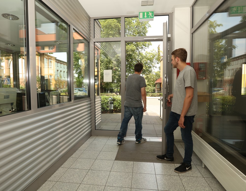 Zwei Männer verlassen die Klinik durch die Pforte.