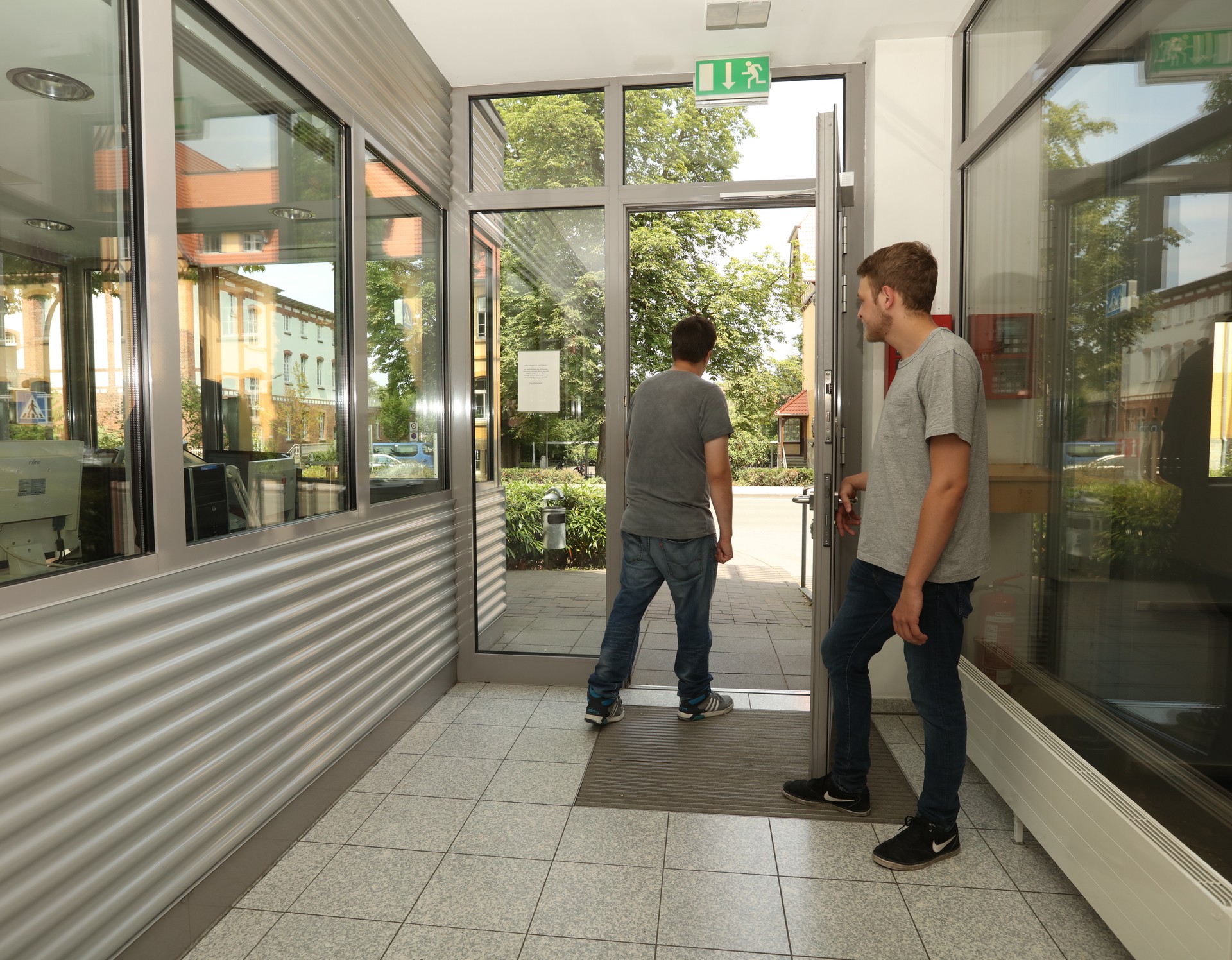 Zwei Männer verlassen die Klinik durch die Pforte.