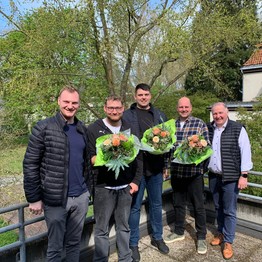 Fünf Männer lachen in die Kamera. Die mittleren drei halten einen Blumenstrauß. (Bild: LWL)