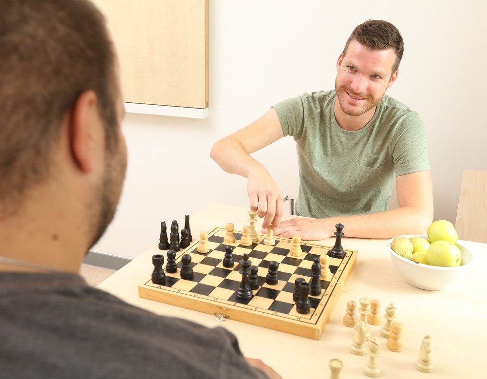 Ein junger Mann spielt mit einem anderen Schach.