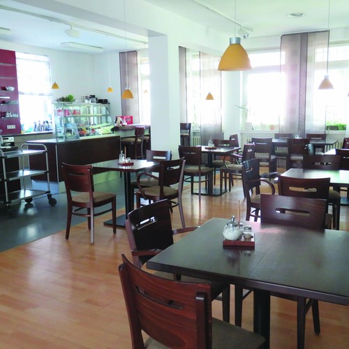 Blick in ein Café mit Theke und Bistrotischen aus Holz (Foto: LWL)