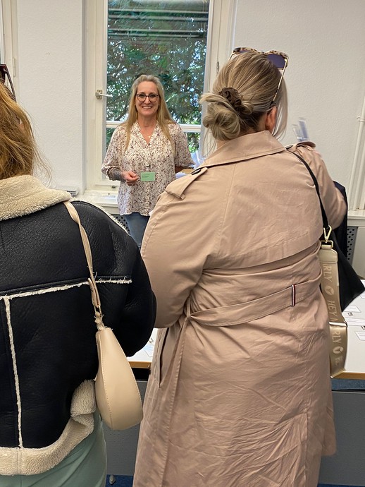 Eine Mitarbeiterin begrüßt zwei Tagungsgäste (Foto: LWL/SchuFi) (vergrößerte Bildansicht wird geöffnet)