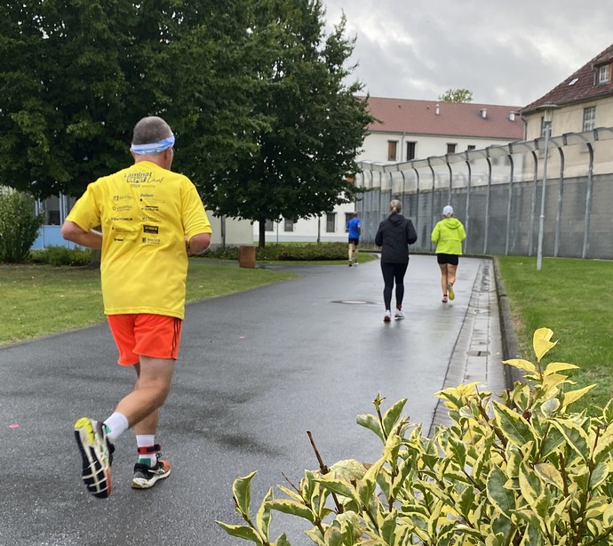 Mehrere Läufer joggen an einem hohen Sicherheitszaun entlang (Bild: LWL/Schufi)