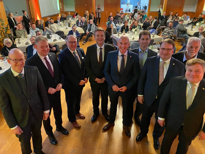 Ein Gruppe von Männern steht vor Publikum in einem Festsaal und lacht in die Kamera (Bild: LWL/Schufi)