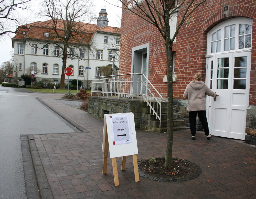 Ein Frau geht durch eine Tür, vor der ein Schild auf die Impfaktion hinweist. (Bild: LWL/SchuFi)